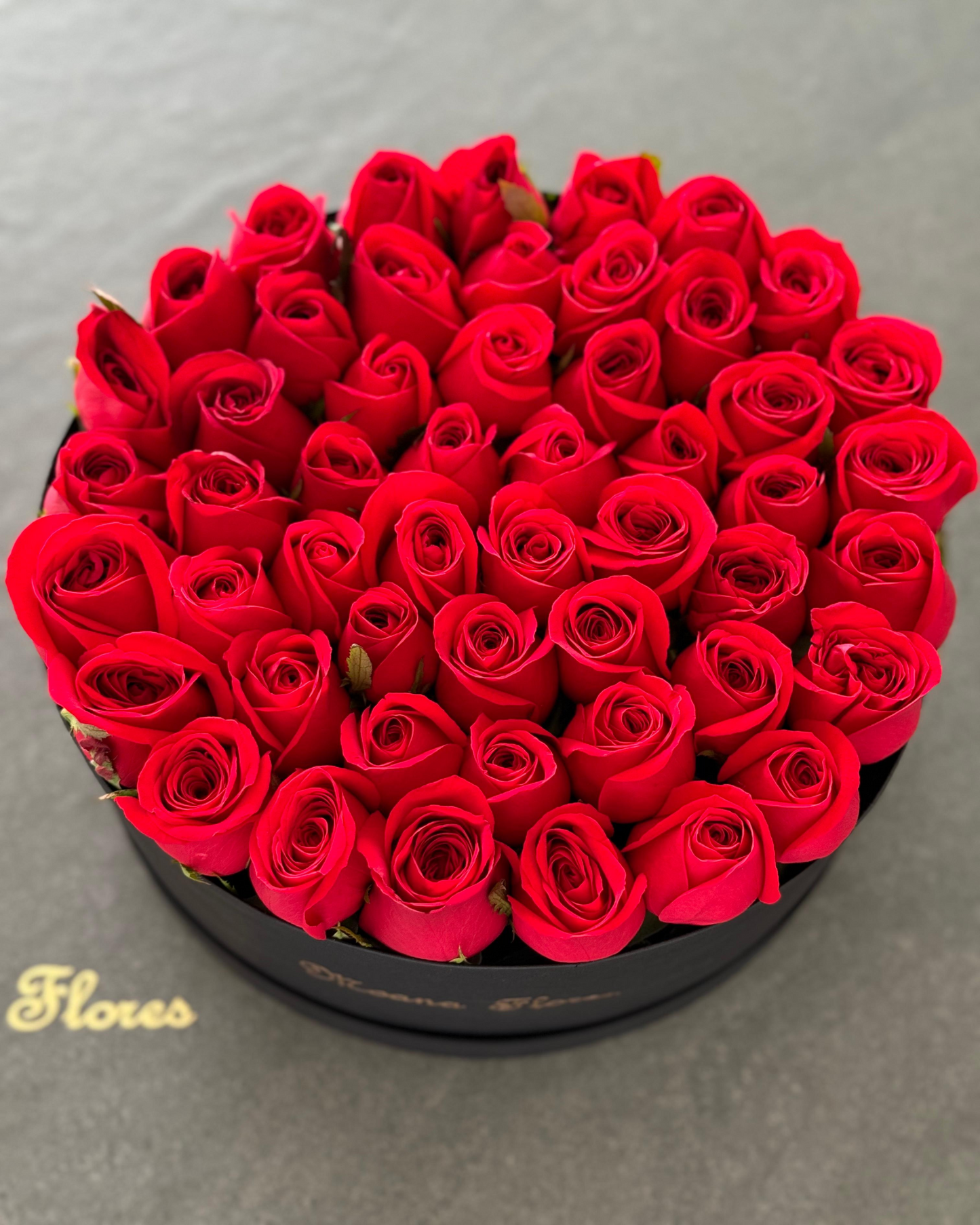 Rosas rojas en caja circular negra.