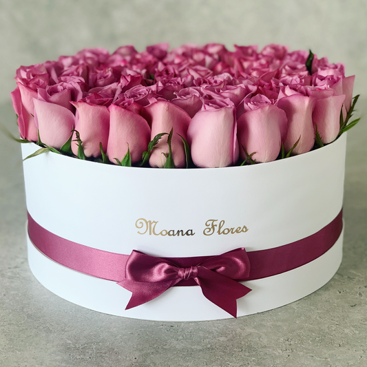 Rosas moradas en caja circular blanca con listón morado.