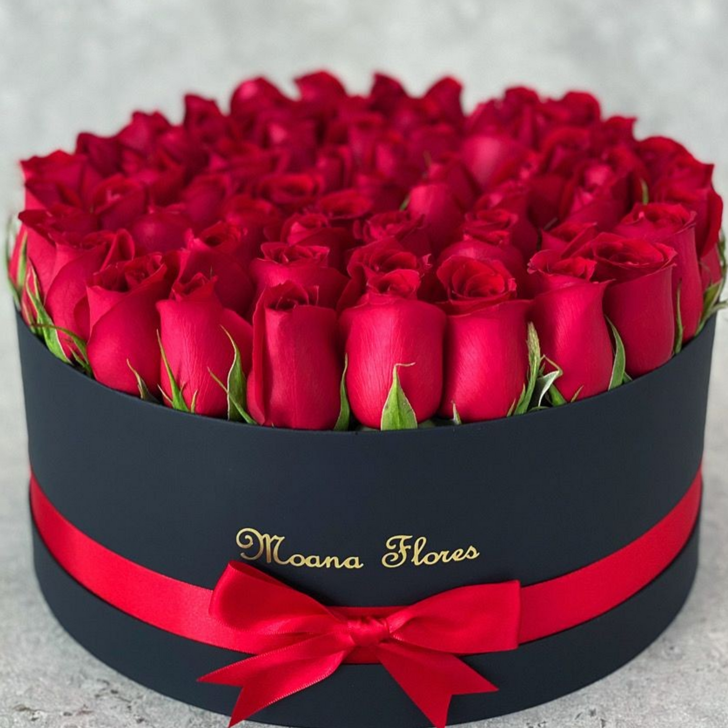 Rosas rojas en caja circular negra con listón.