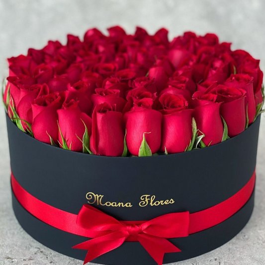 Rosas rojas en caja circular negra con listón.