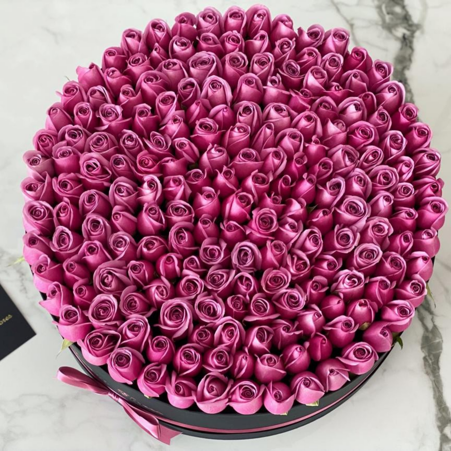 Rosas moradas caja circular negra con listón.