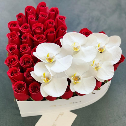 Rosas rojas con orquídeas blancas caja de corazón regular.