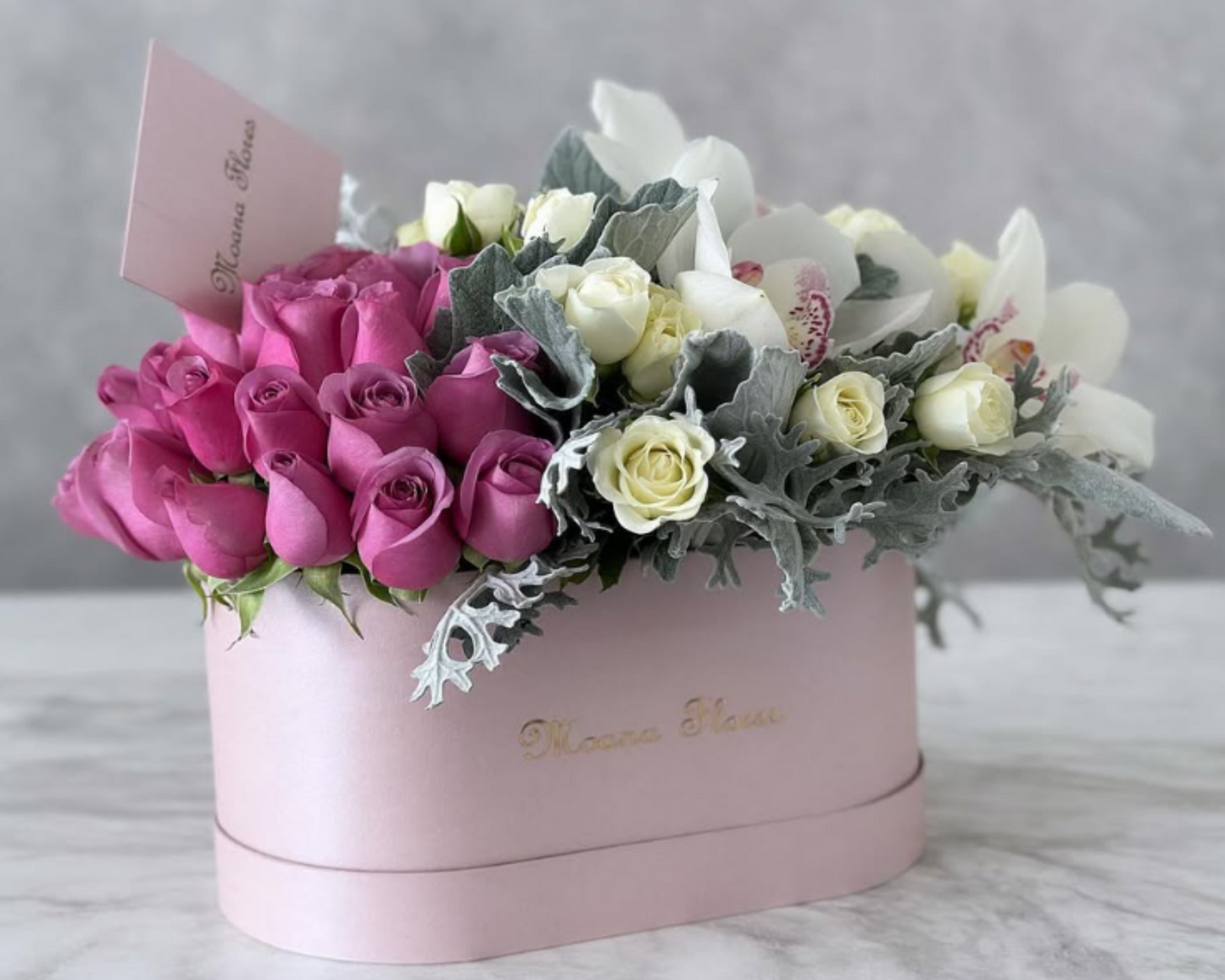 Blushera con rosas moradas con orquídeas blancas y follaje.