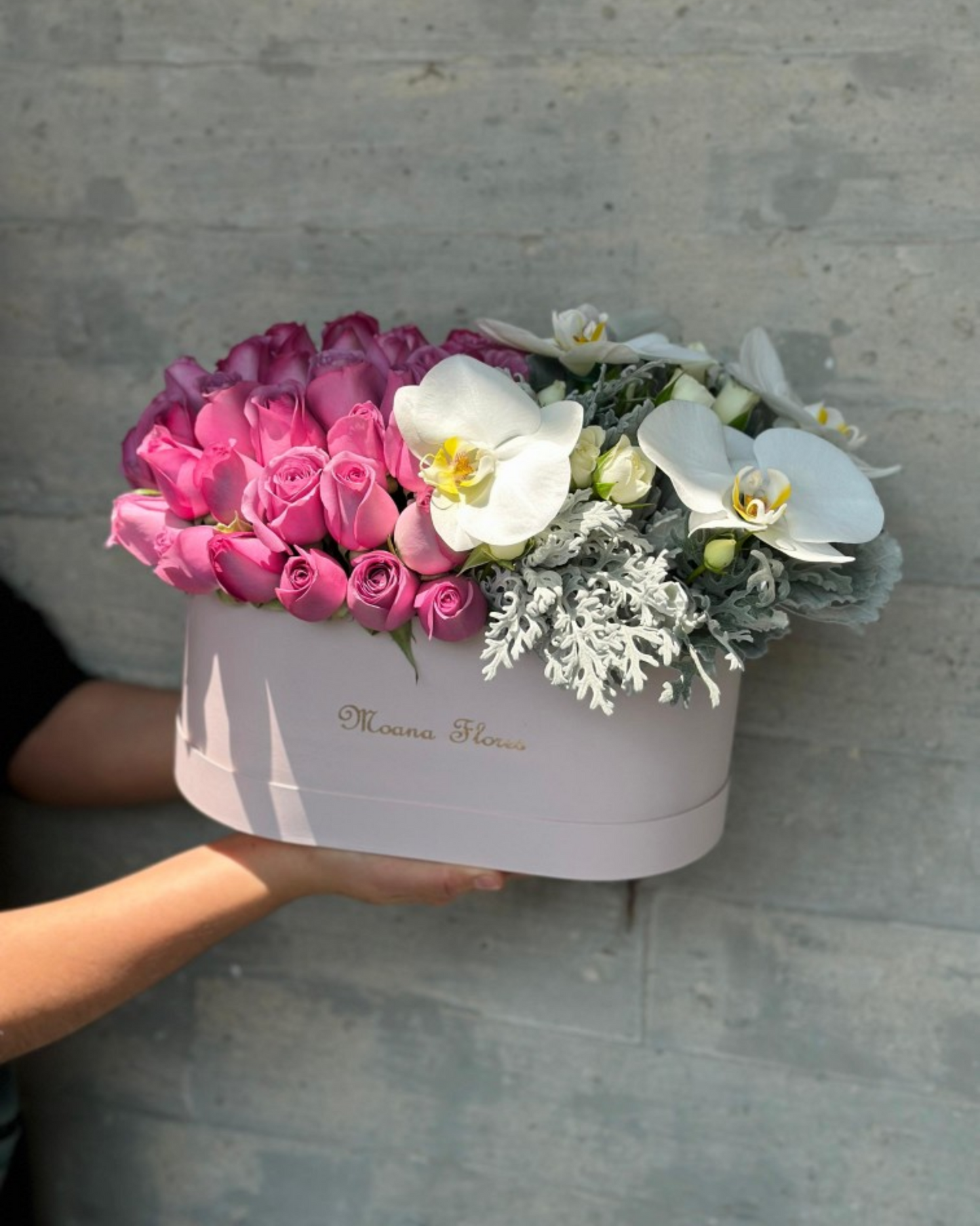Blushera de rosas moradas con follaje y orquídeas blancas.