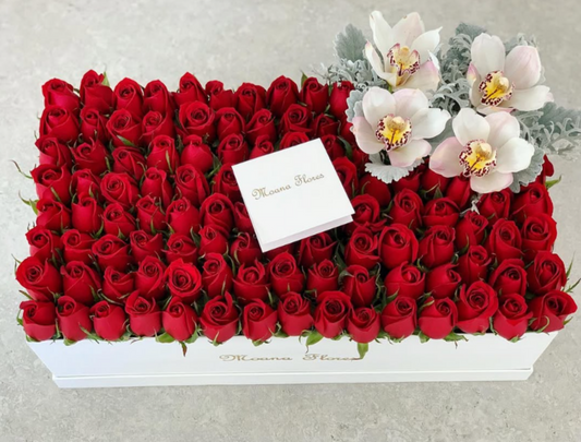 Rosas rojas y follaje con orquídeas blancas.