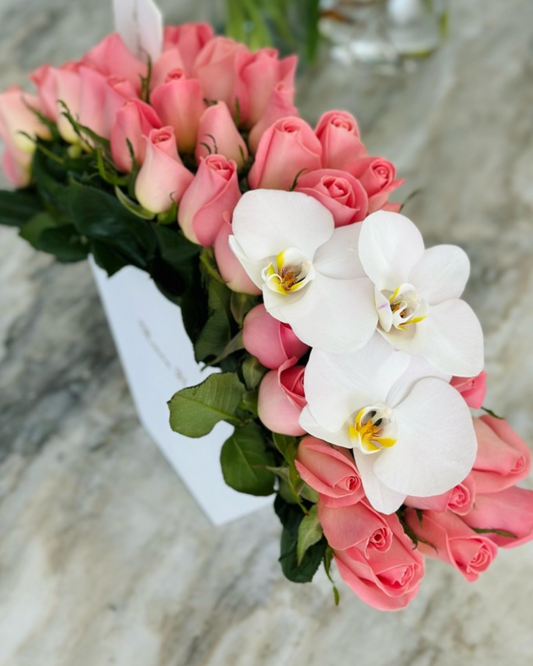 Rosas hermosas con follaje con orquídeas blancas