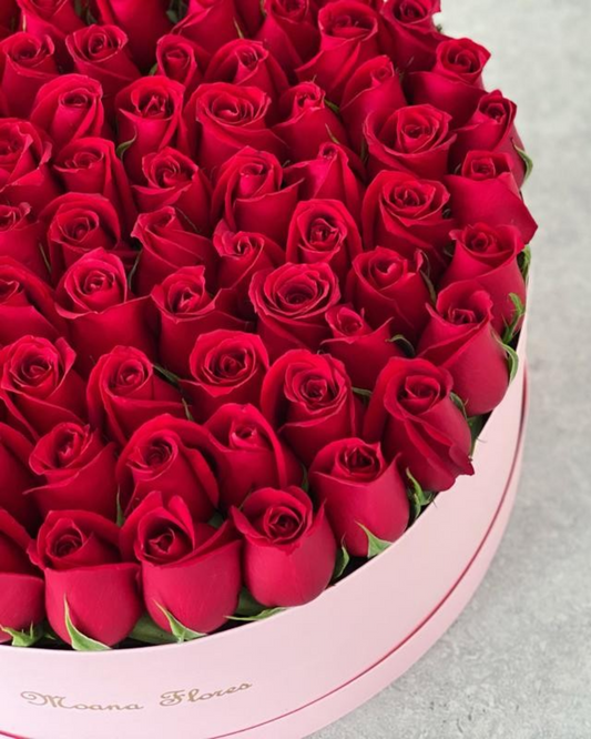 Rosas rojas en caja circular intermedia rosa.