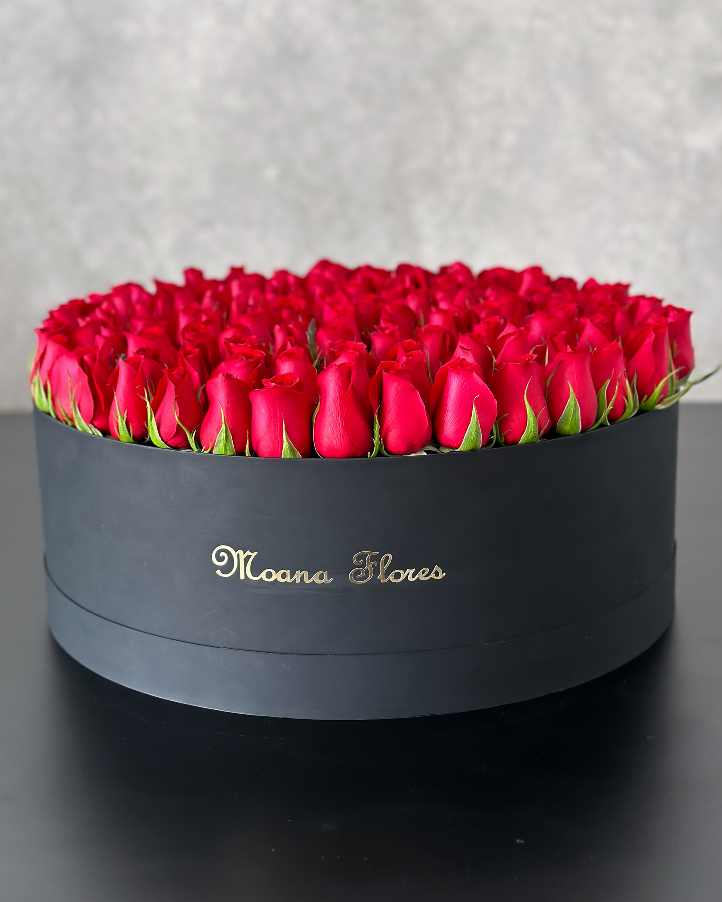 Rosas rojas en caja circular negra mediana