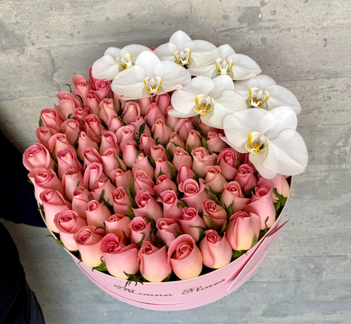 Rosas hermosas en caja circular rosa con orquideas