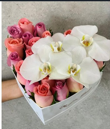Rosas moradas y hermosas con orquídeas en caja de corazón.