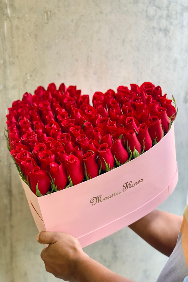 Rosas rojas en caja de corazón rosa intermedio.
