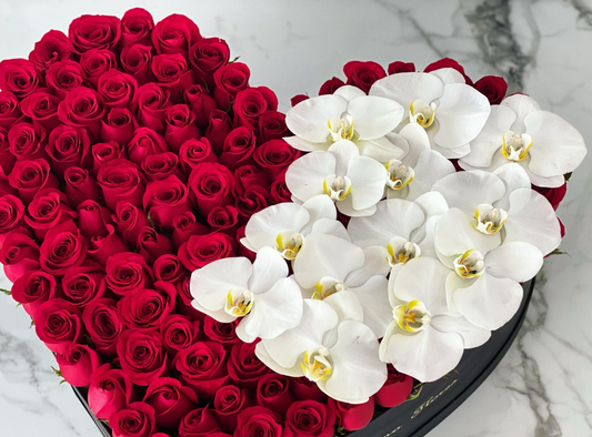 Rosas rojas con orquídeas blancas en caja corazon mediano