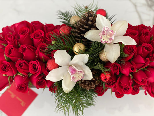 Rosas rojas, orquídeas blancas en caja marrón.