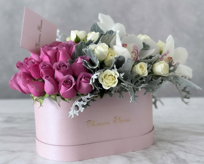 Blushera de rosas moradas con follaje y orquídeas blancas.