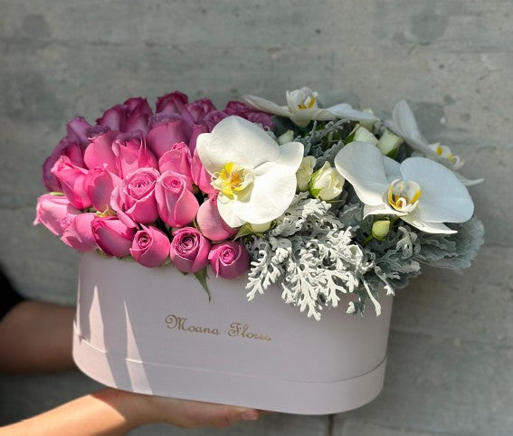 Blushera con rosas moradas y orquídeas blancas y follaje .