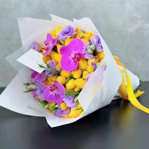 Bouquet de rosas amarillas, lisianthus lila y orquídeas moradas.